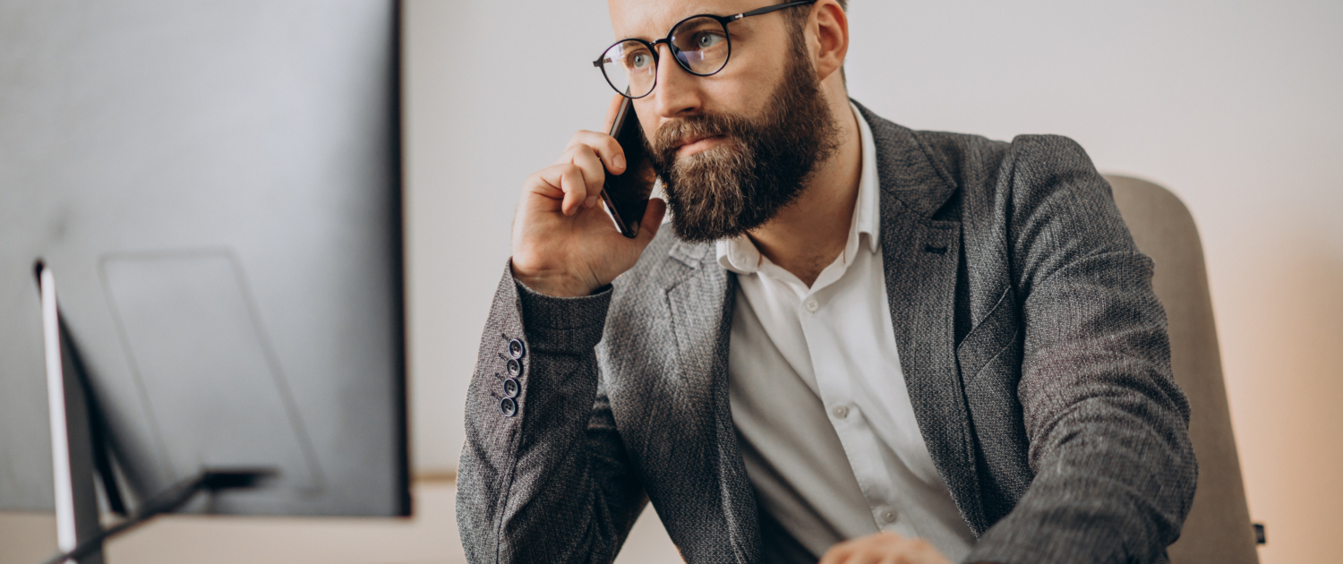 Young business man talking on phone and working on computer