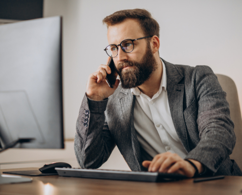 Young business man talking on phone and working on computer